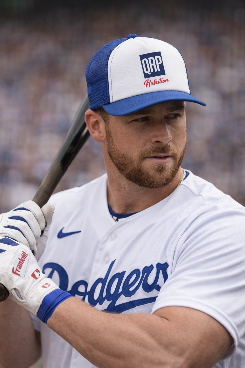 Baseball player in a Dodgers uniform with a QPR Nutrition cap, holding a bat.