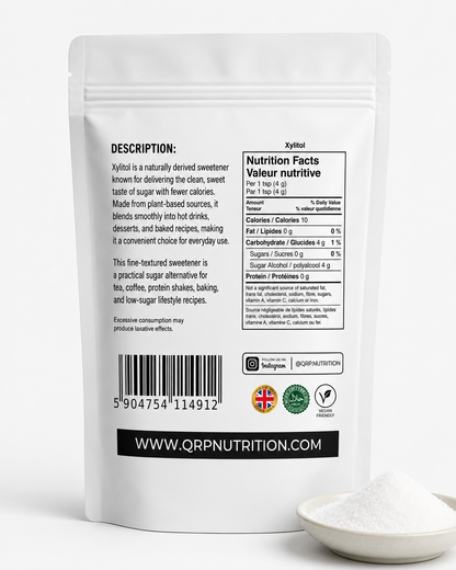 The back of a white stand-up pouch of QRP Nutrition Xylitol sweetener, shown on a white background with a small pile of white powder in a spoon in the lower right corner.